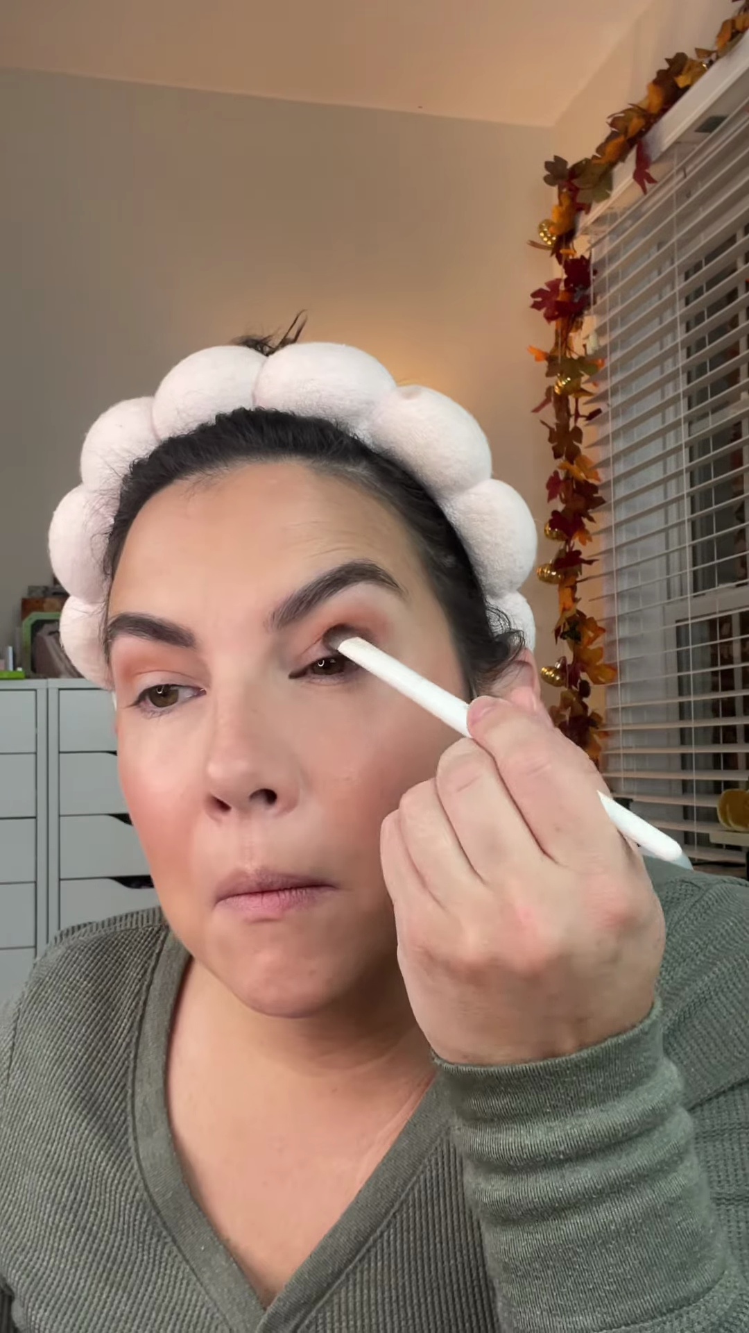 Deep burgundy-brown eyeshadow being applied to the eyelid with precise patting motion