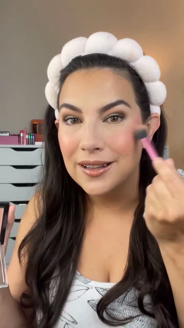 Emily applying Wet n Wild Precious Petals highlighter over the blush