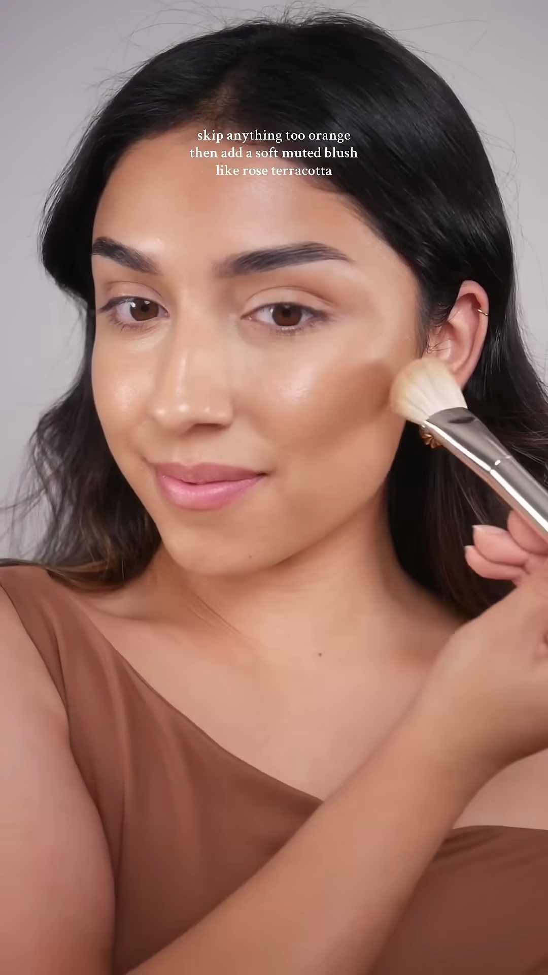 Mia applying bronzer with a fluffy brush to her olive skin tone