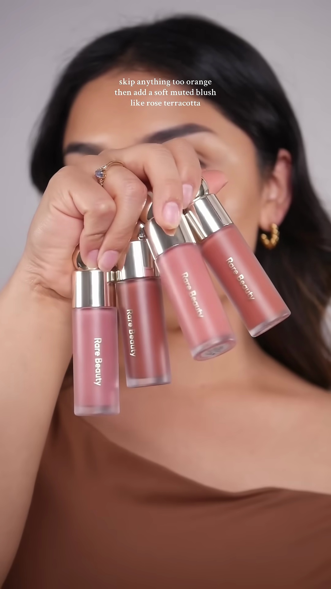 Close-up of muted rose blush being applied to olive skin