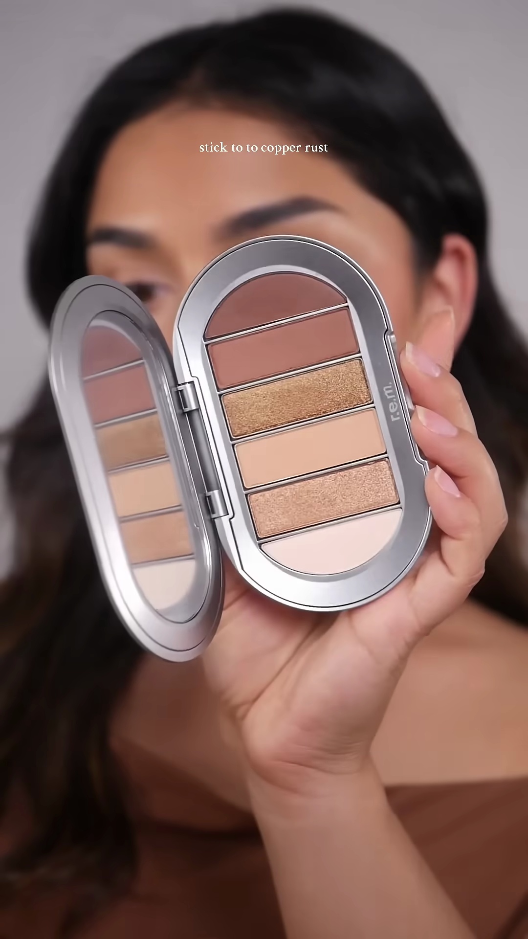 Mia applying bronze eyeshadow to her eyelids using the RM Beauty palette