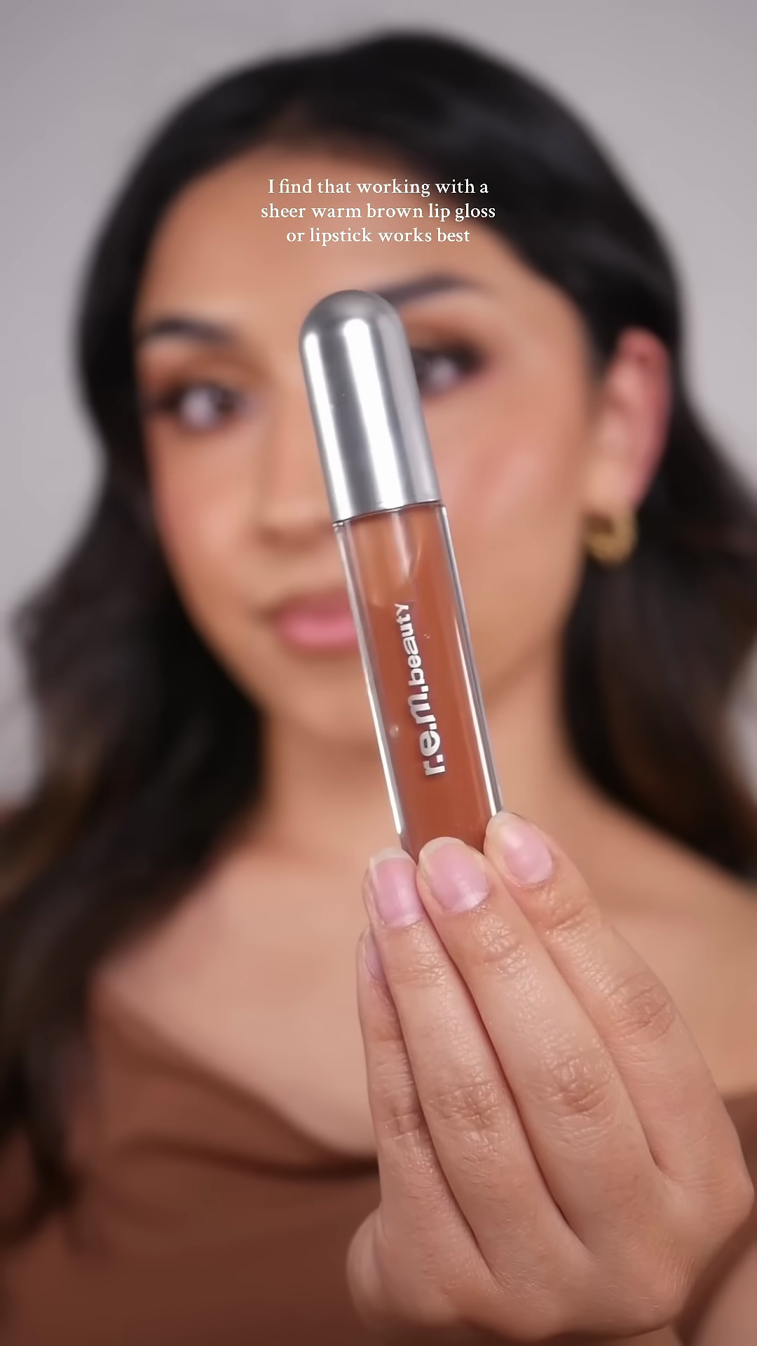 Mia applying sheer brown lip gloss to complete her fall makeup